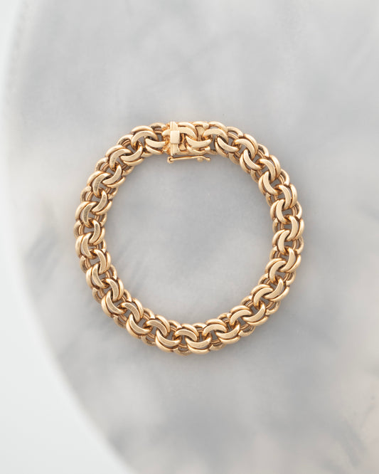 Gold chain bracelet on a light gray background