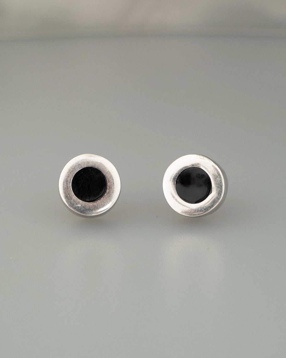 Pair of silver eye-shaped earrings on a gray background